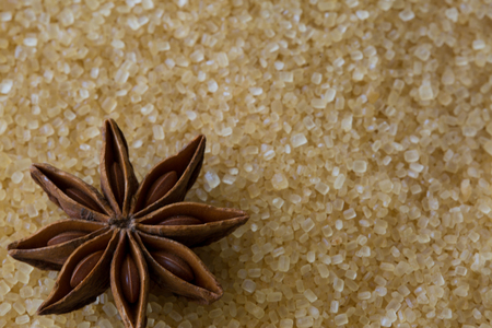 Anise star on brown cane sugar granules, close up, macro.の写真素材