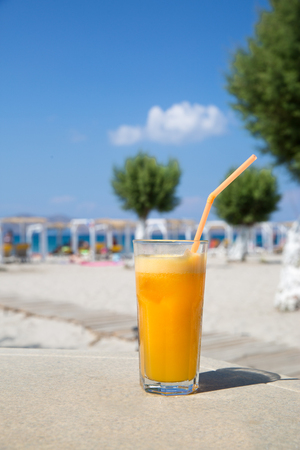 Glass of fresh orange juice on white beach sea view coast background. Relax and vacation concept.の写真素材