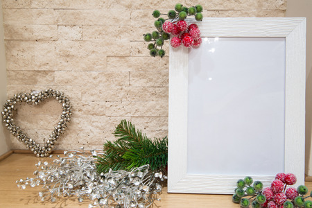 Christmas mock up, fir branches, silver Christmas decor and silver heart with red and green berries frame, brick wall background.の写真素材