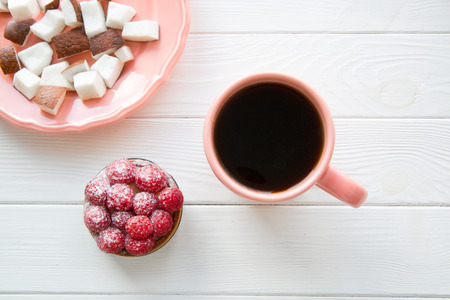 Healthy sweets and pink plate and a cup of coffee on white table background, top view.