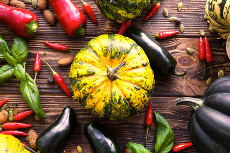 Bright autumn harvest, assortment of fresh vegetables, different kinds of squash and pumpkins on brown background. Top view. の写真素材