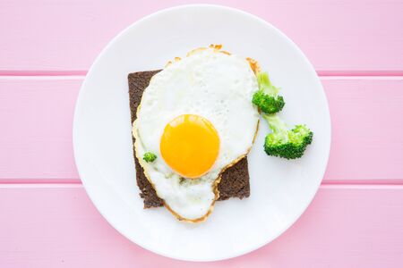 Fried egg and toast for breakfast on wooden table, top view. Colorful background, conceptual healthy...
