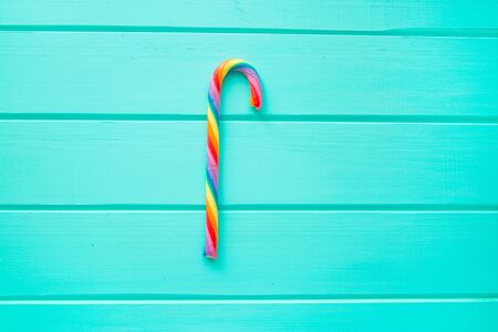 Rainbow candy stick on turquoise wooden background. Creative trendy background, top view.の写真素材