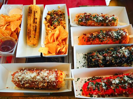 Different kinds of tasty grilled sweet corn with cheese, chili, paprika and nachos, close up.           の写真素材