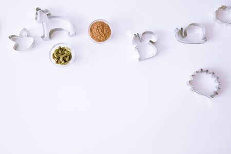 Animal cookie cutters on white table, top view. Cinammon and cardamom spice. Space for text,...