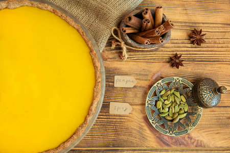 Pumpkin spice autumn pie with cinnamon on rustic wooden table, top view. Seasonal homemade pastry.