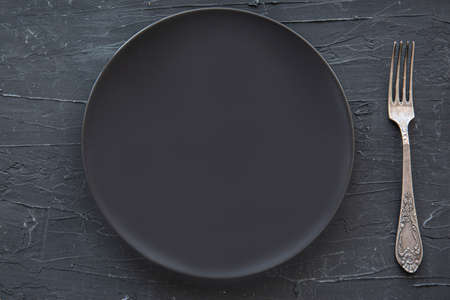 Empty black plate on black stone, top view.の写真素材