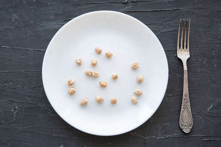 A little bit of dried chickpea in white plate, unhealthy diet concept or crisis concept.の写真素材