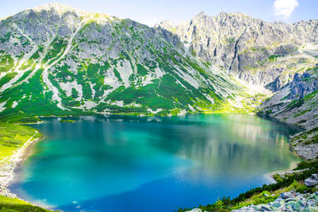 Beautiful lake high in the mountains. Turquoise green waters, peaks with snow. bright summer day.の写真素材
