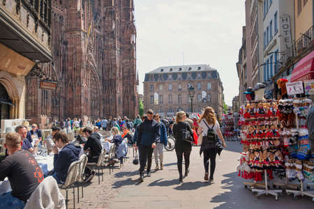 2 of May 2022, Strasbourg, France. A lot of people sitting in restaurants in the main square near the Cathedral of Our Lady of Strasbourg. Souvenirs shops.のeditorial素材