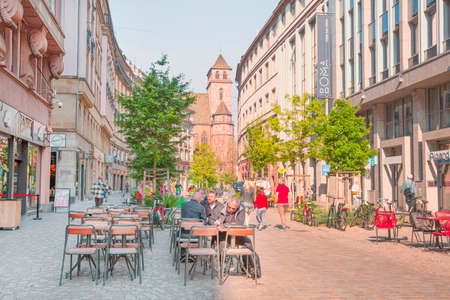 2 of May 2022, Strasbourg, France. Saint Thomas church and people sitting in the restaurant.