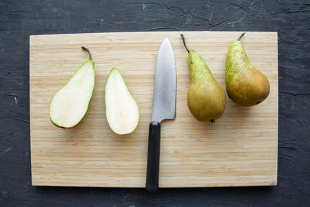 Juicy pears fruit on cutting board and knife, close up, top view.の写真素材