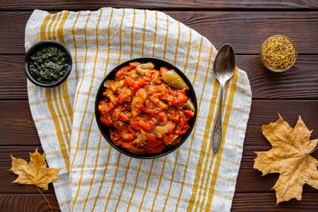 Tasty fall vegetable stew on kitchen towel on brown wooden table, top view. autumn leaves decorations.の写真素材