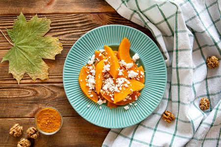 Autumn pumpkin salad with cheese. Dietic tasty fall food, top view. Bright colors and wooden rustic background.の写真素材