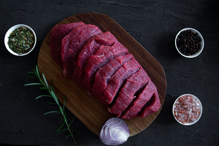 Raw red meat on black marble textured background, top view.の写真素材