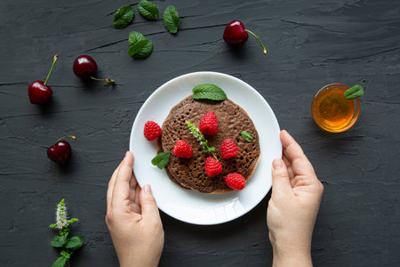 Tasty homemade chocolate pancakes with fresh fruits and honey, top view.の写真素材