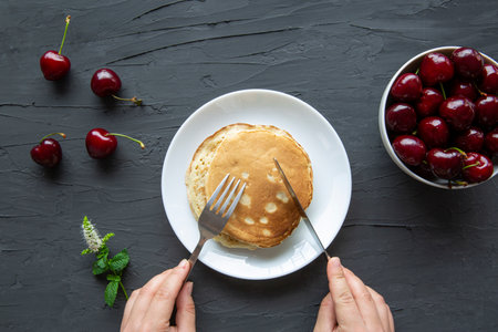 Tasty homemade pancakes with fresh cherry on black background, top view.の写真素材