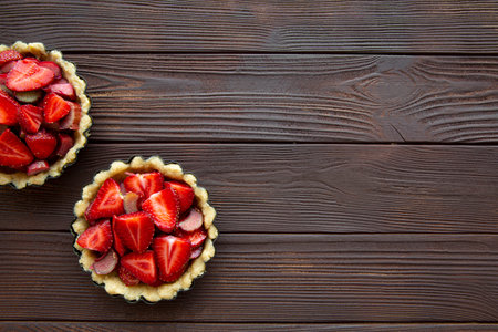 Delicious strawberry tarts on brown wooden background, top view. Copy space, free space for text.の写真素材