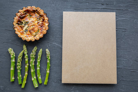 Little tart or quiche with asparagus on black marble background, space for text and recipe, copy space, top view.の写真素材