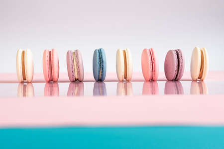 Multicolored macarons on a white, pink background.の写真素材