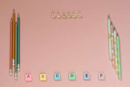 School supplies, an eraser, pen, pensil, letters on the biege background. Top view frame.の写真素材