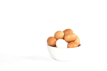 Eggs lay on white background. Food ingredient. Close-up view of raw chicken eggs in bowl on isolated...