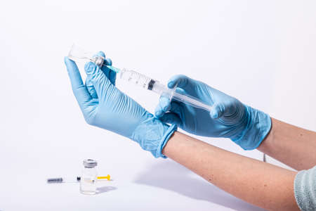 Doctor, researcher holds hands syringe in blue glove holding flu, measles, rubella or hpv vaccine and syringe with needle vaccination for human.の写真素材