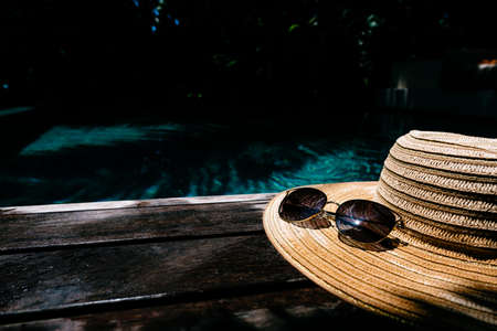 Straw hat and sunglasses on a wooden background, pool area. Top view. Travel and beach vacation, copy space for text.の写真素材