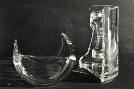 Two halves of a broken cup stand on a black background. Broken.の写真素材