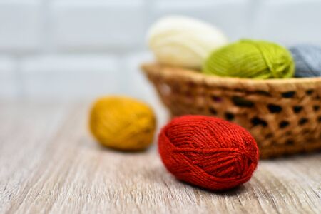 Multi-colored clews for knitting in a basket on a wooden background. Place for an inscription. Iron knitting needles, felt-tip pens. Blurred background.の写真素材