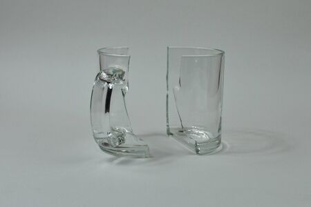 Two halves of a broken cup stand on a gray background.の写真素材