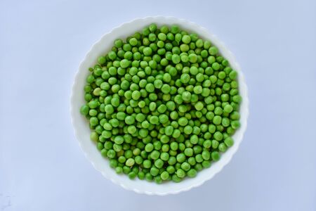 Green peas in a white bowl on a white backgroundの写真素材
