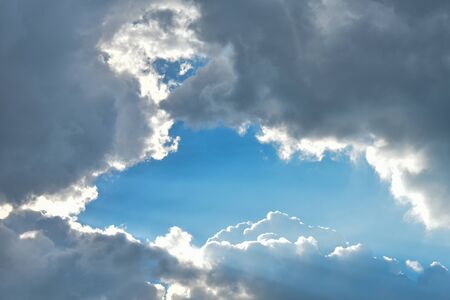 Blue sky surrounded by gray clouds. Place for an inscription
