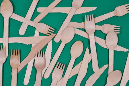 Wooden spoons, forks, knives on a green background. Zero waste concept. View from the top.