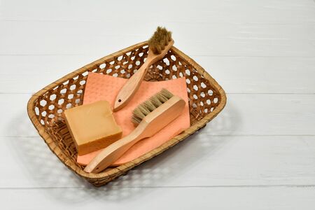 Wooden cleaning brushes and solid natural soap in a basket on a white background. Zero alternative for a plastic product. Eco-friendly concept.の写真素材