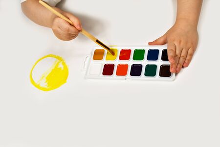 Childrens hands are painted with a brush and watercolors. Childrens creativity, painting, early development.の写真素材