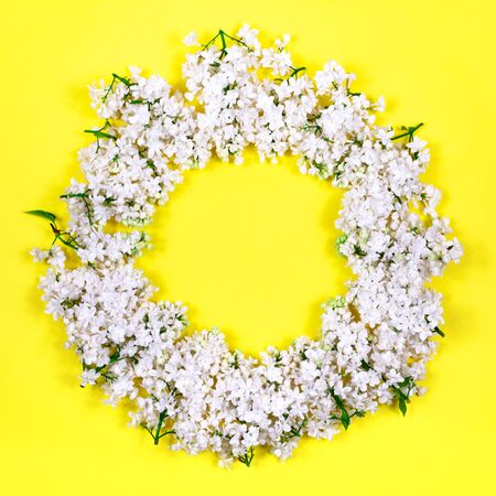 A wreath of white lilac on a yellow background. Place for an inscription. View from above. Blank for postcards.の写真素材