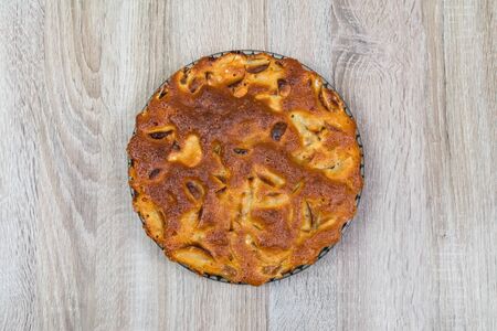 Homemade baked apple pie, in a plate, on a wooden table, ready to eat.