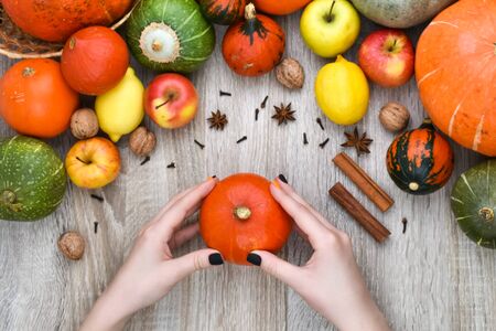 Autumn background. Female hands with a beautiful manicure hold an orange pumpkin on an autumn background. View from above.の写真素材