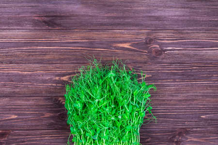 Green pea sprouts on a wooden textured dark background. Place for an inscription