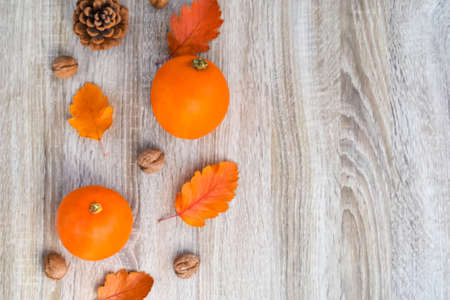 Autumn composition. Pumpkins, nuts, pine cone, leaves on a wooden background. Fall. Flat lay, top view, copy spaceの写真素材