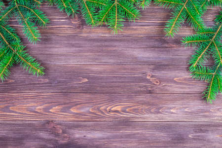 Green branches of a Christmas tree on a dark wooden background. Place for an inscription. The basis for the postcard. Copyspace.の写真素材