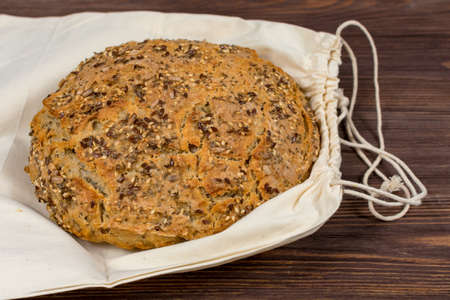 Homemade sourdough wheat bread with whole grain flour on a white cloth bag. Delicious crunchy about...