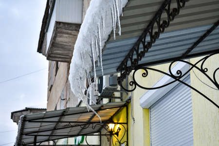 Transparent icicles from the frozen melting snow will rise on the roof of the balcony.の写真素材