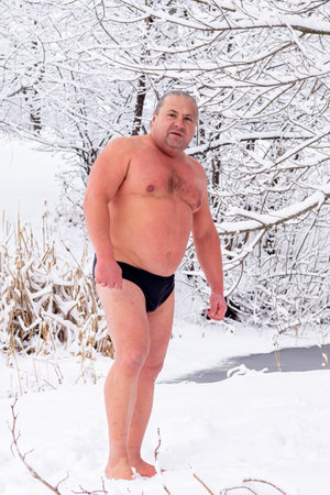 Portrait of a handsome man after swimming in an icy river on the background of a snowy winter forest.の写真素材