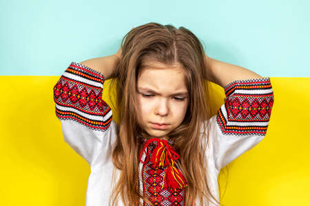 A girl is crying, holding a STOP poster on the background of the Ukrainian flag. Stop the war in Ukraine. The concept of peace in Ukraine.の写真素材