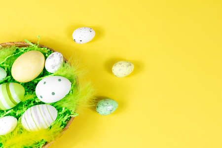 Easter nest with eggs and feathers on a yellow background. View from above. Place for text, lettering. Easter concept.の写真素材