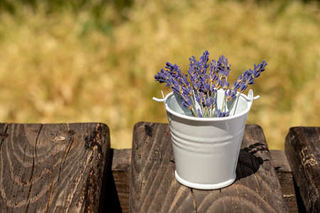 Bouquet of purple lavender flowers, in a white bucket on a wooden background. Place for an inscription. Selective focus.の写真素材