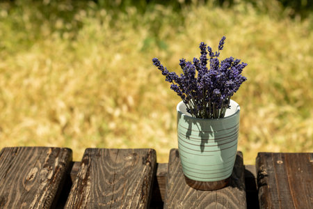 Bouquet of purple lavender flowers, in a green vase on a wooden background. Place for an inscription. Selective focus.の写真素材