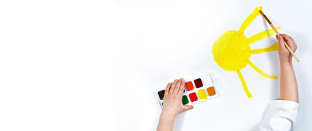 Banner. Childrens hands draw the sun in watercolor. Childrens creativity, painting, early development. Place for an inscription.の写真素材